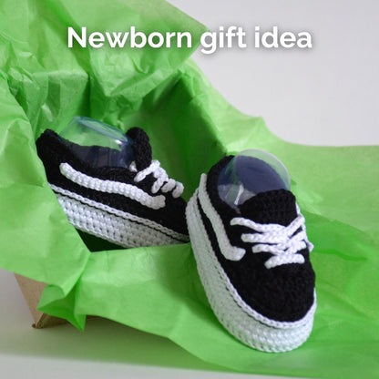 Black and white crochet baby sneakers in green gift wrap — newborn gift idea PDF crochet pattern
