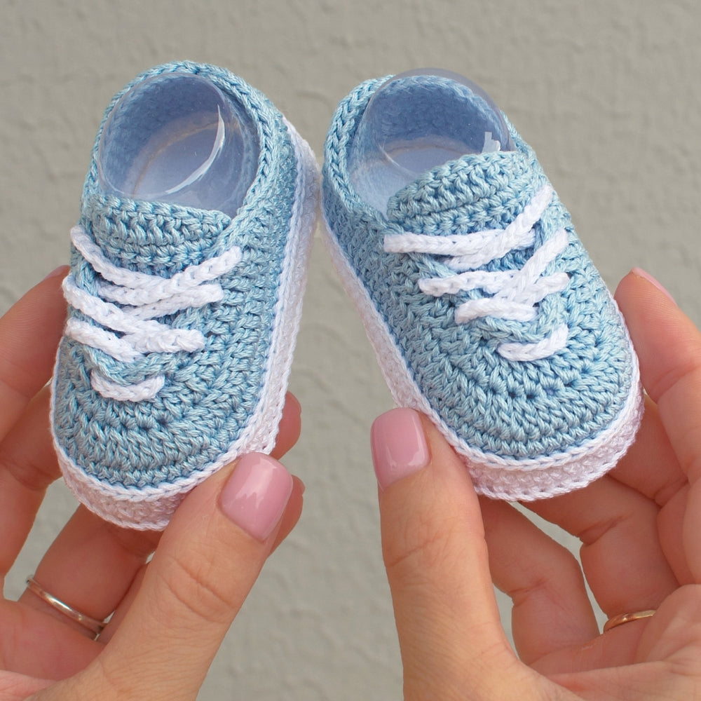 Handmade blue crochet baby sneakers shown in hands
