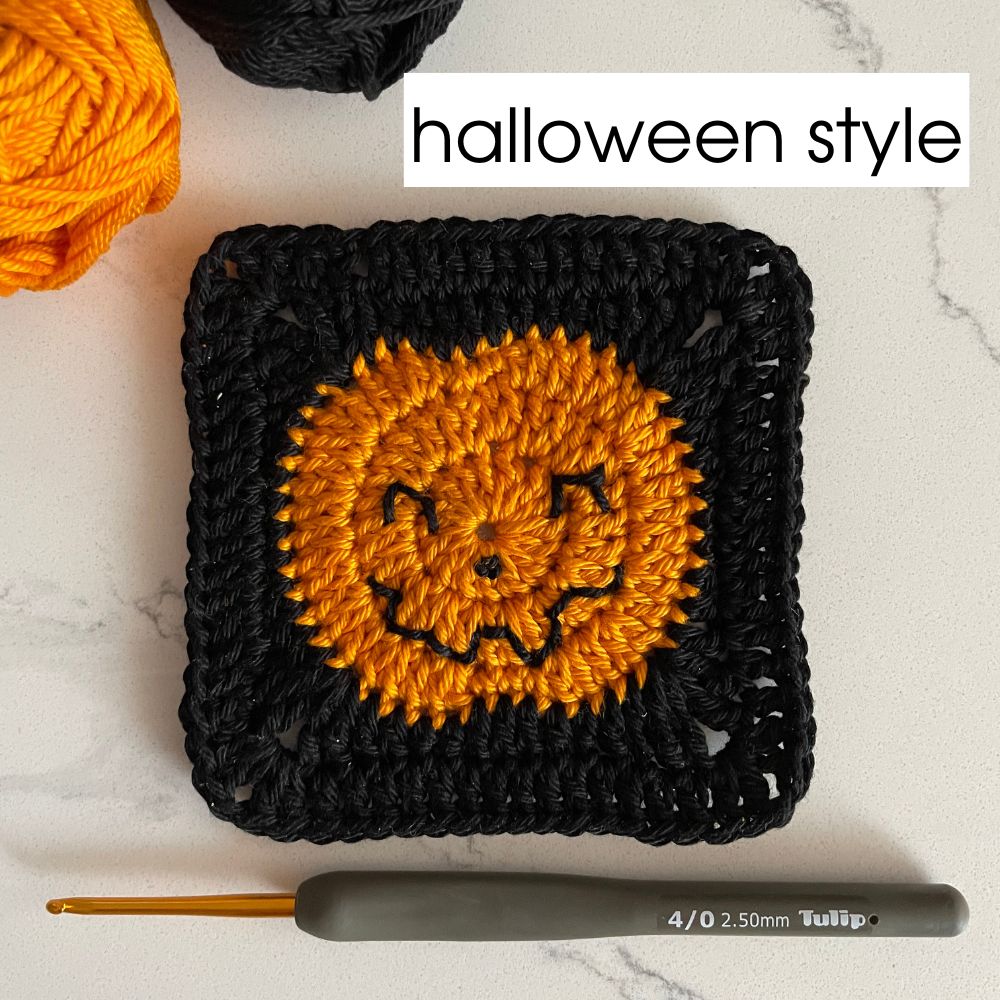 Halloween-themed crochet granny square with jack-o'-lantern pumpkin on black background
