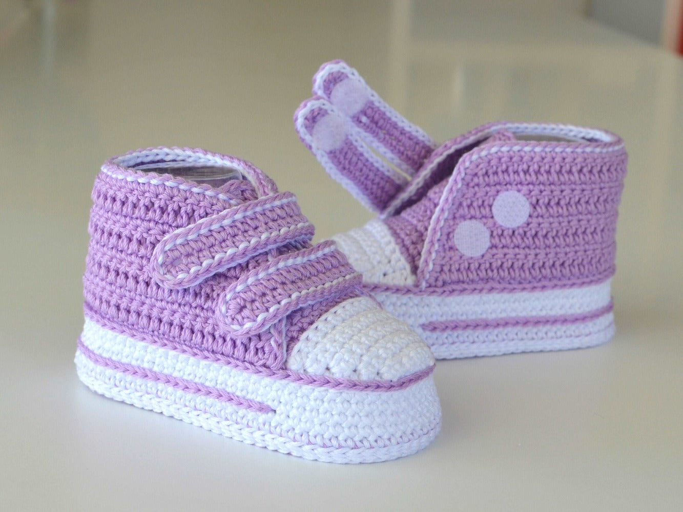 Stylish crochet baby shoes with dual hook-and-loop closure.